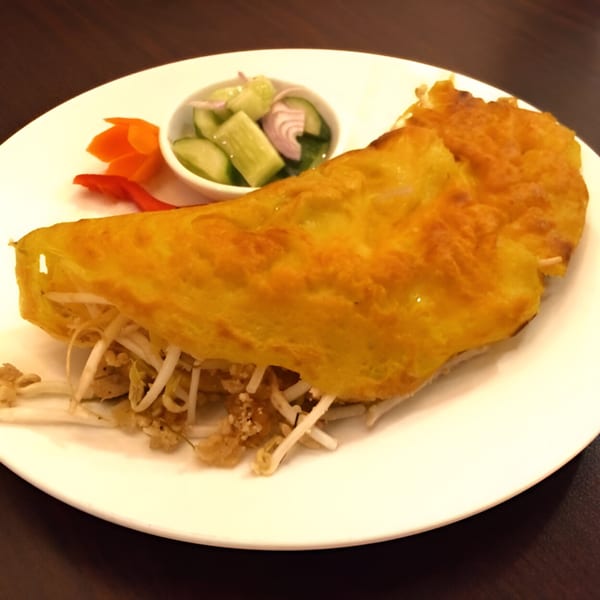 Golden Thai omelet filled with bean sprouts, served with pickled cucumbers and carrots.