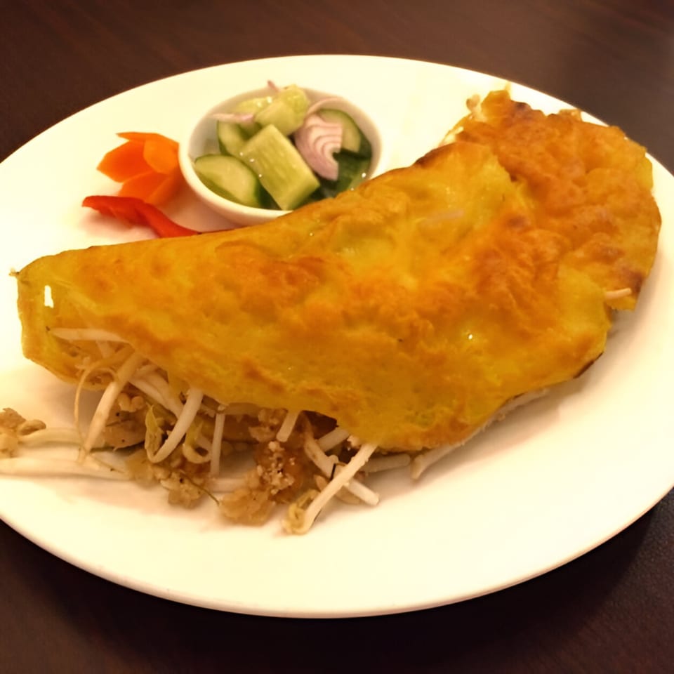 Golden Thai omelet filled with bean sprouts, served with pickled cucumbers and carrots.
